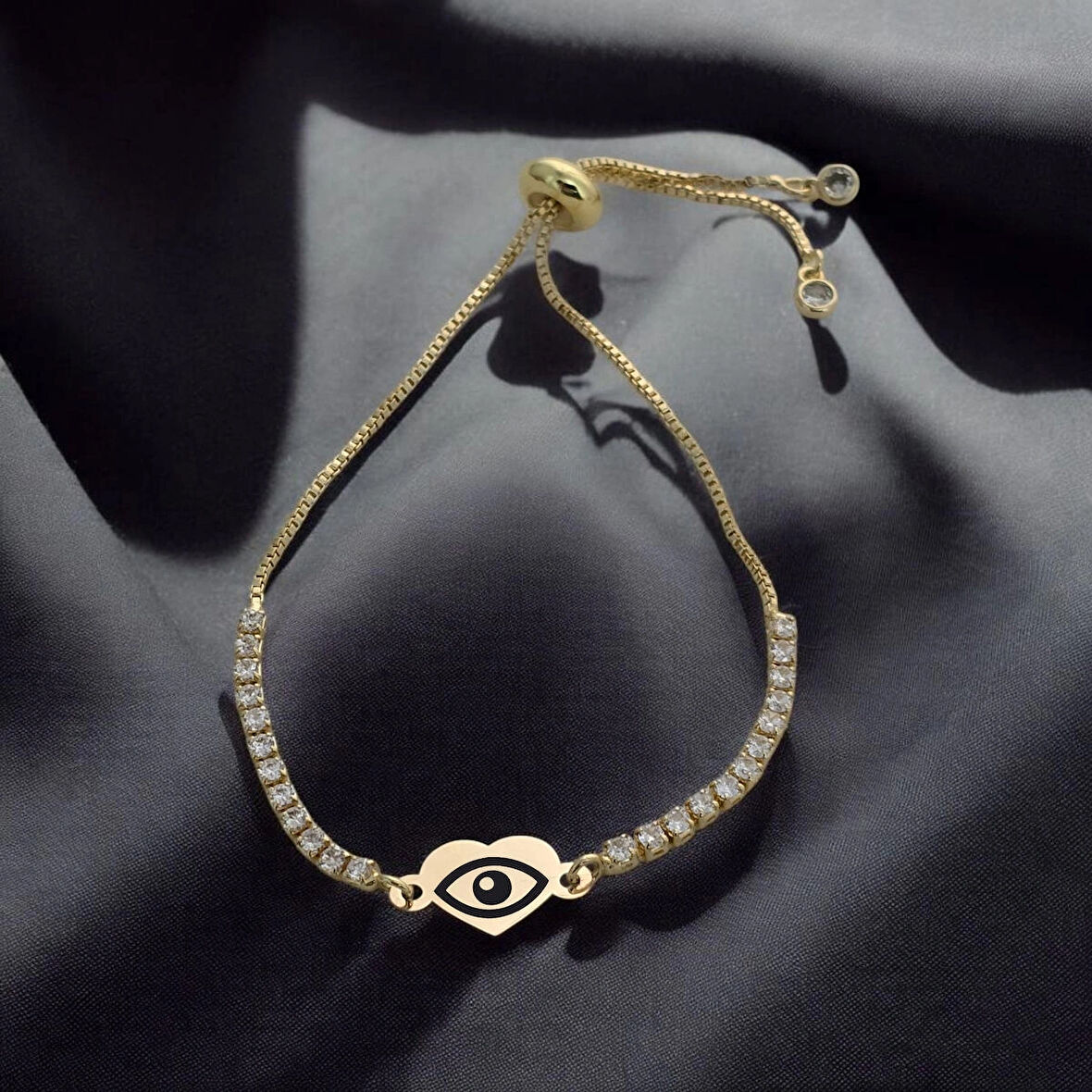 Nazardan Koruyan Kalp Motifli ve Parlak Beyaz Taşlı 14 Ayar Altın Plakalı Nazar Göz Bilekliği